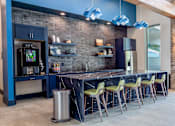 Thumbnail 13 of 36 - A modern kitchen with a bar area and a trash bin.